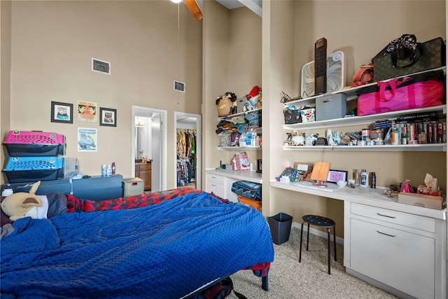 bedroom with a towering ceiling, built in desk, and light carpet