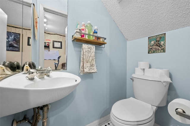 bathroom with lofted ceiling, toilet, and a textured ceiling