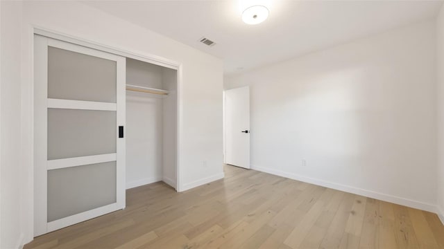 unfurnished bedroom featuring light hardwood / wood-style flooring and a closet