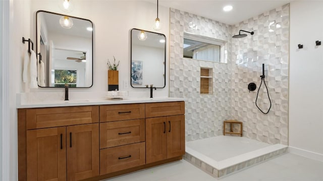 bathroom featuring ceiling fan, tiled shower, vanity, and tile patterned floors