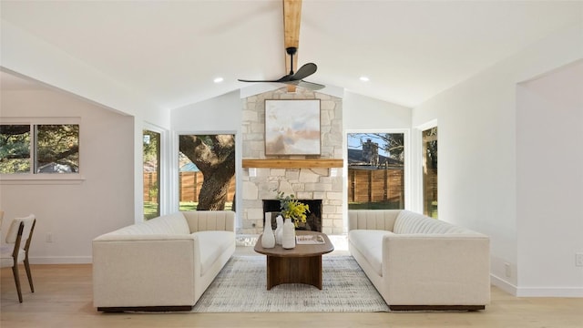 living room with ceiling fan, a fireplace, light wood-type flooring, and vaulted ceiling with beams