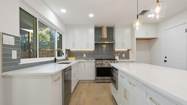 kitchen featuring stainless steel appliances, sink, white cabinets, and wall chimney exhaust hood