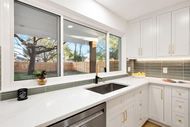 kitchen featuring sink, decorative backsplash, stainless steel dishwasher, and white cabinets