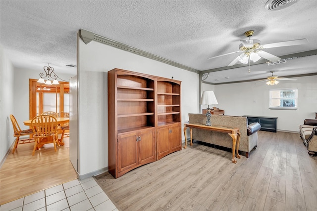 living room with ceiling fan, crown molding, light hardwood / wood-style floors, and a textured ceiling