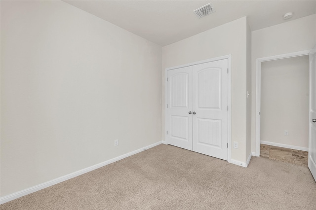 unfurnished bedroom with light colored carpet and a closet