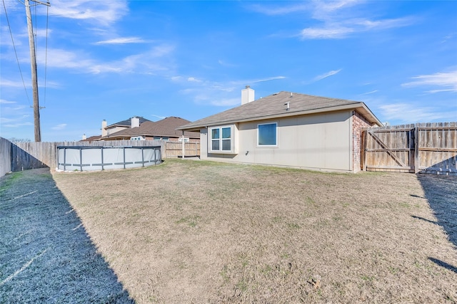 rear view of house with a fenced in pool and a yard