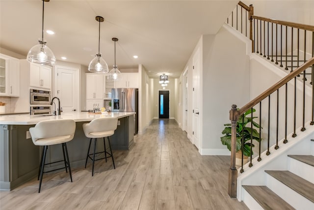 125 Serene Hilltop Cir, Austin, TX 78738 - kitchen with light wood-type flooring, white cabinetry, light countertops, a kitchen bar, and hanging light fixtures