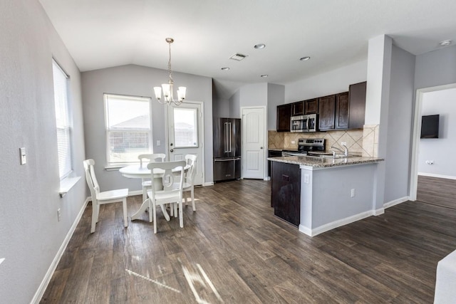 kitchen with vaulted ceiling, appliances with stainless steel finishes, decorative backsplash, light stone countertops, and dark brown cabinets