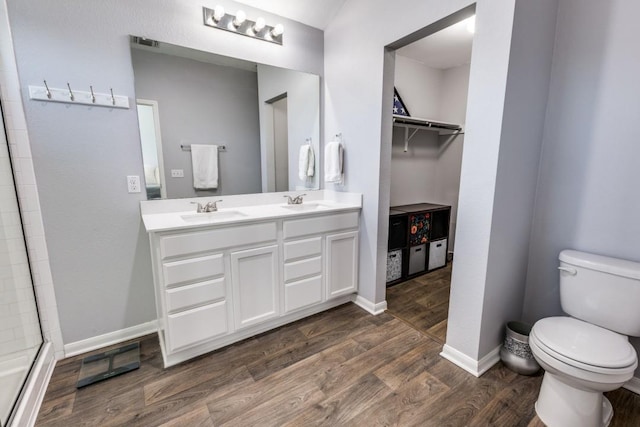 bathroom featuring vanity, hardwood / wood-style flooring, a shower with door, and toilet