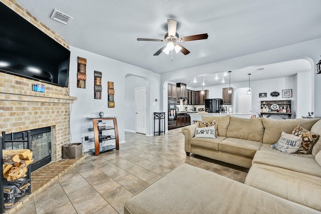 living room featuring a brick fireplace and ceiling fan