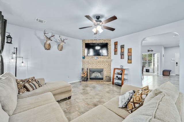 living room featuring ceiling fan and a brick fireplace