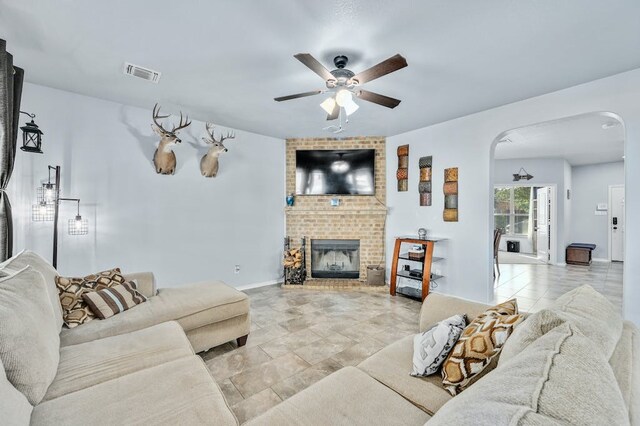 1712 Uhland Dr, Leander, TX 78641 - living room featuring a ceiling fan, arched walkways, and a brick fireplace
