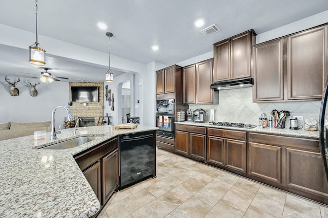 kitchen with sink, hanging light fixtures, black dishwasher, dark brown cabinetry, and light stone countertops