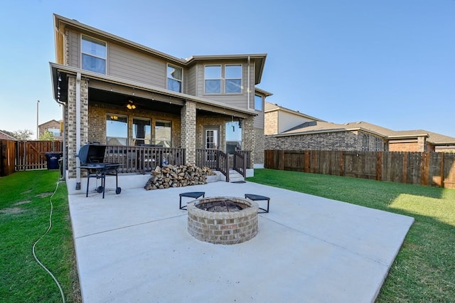 back of property with a yard, a patio area, and an outdoor fire pit