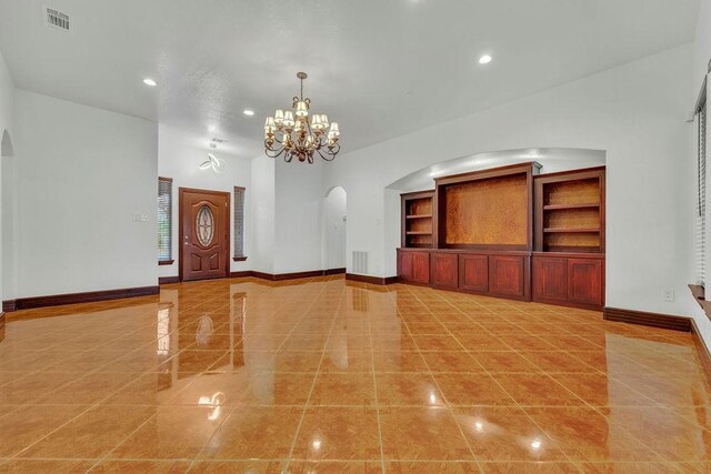 unfurnished living room with built in shelves and a chandelier