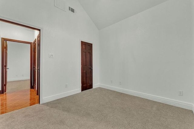 carpeted spare room with high vaulted ceiling