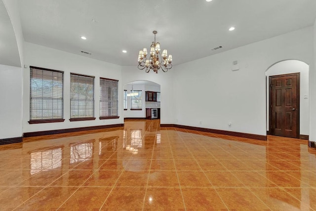 unfurnished living room featuring tile patterned flooring, a notable chandelier, and plenty of natural light