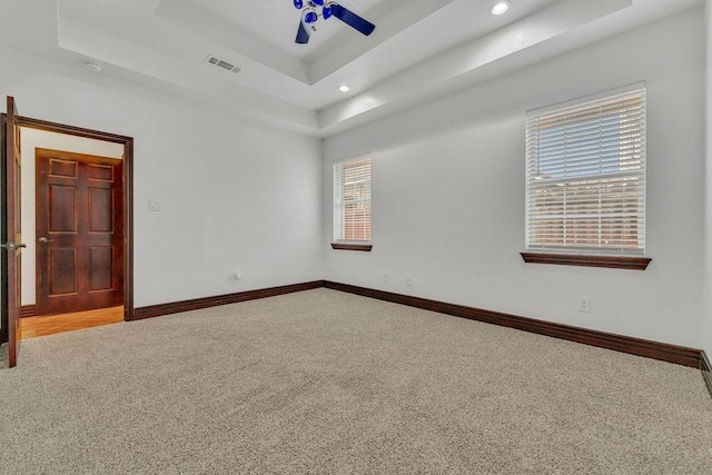 unfurnished room with a tray ceiling, carpet floors, and ceiling fan