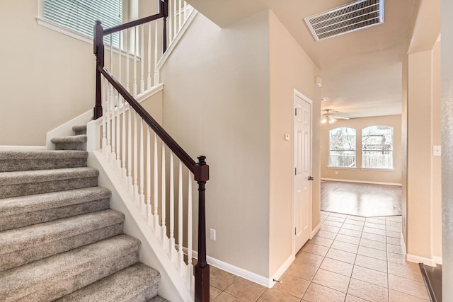 stairway with ceiling fan and tile patterned floors