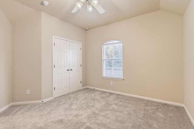 unfurnished bedroom featuring lofted ceiling, light carpet, ceiling fan, and a closet