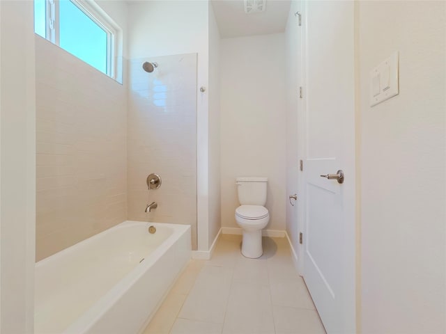 bathroom featuring tile patterned flooring, tiled shower / bath, and toilet