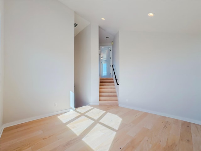 empty room with vaulted ceiling and light wood-type flooring