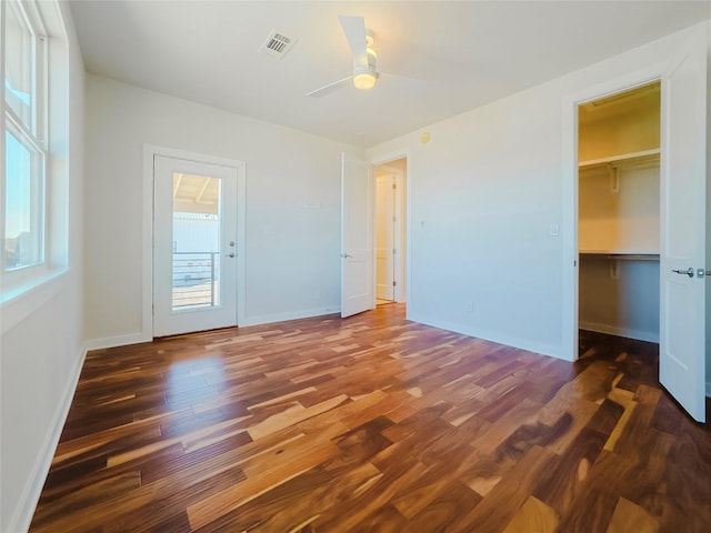 unfurnished bedroom with dark hardwood / wood-style floors, ceiling fan, a spacious closet, and a closet