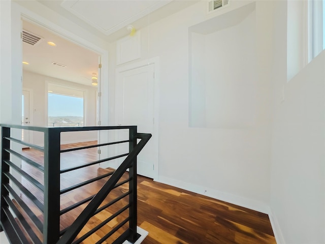 staircase with ornamental molding and hardwood / wood-style floors