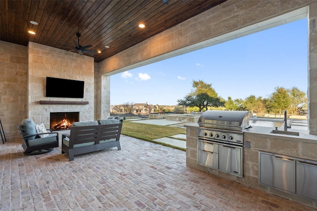 view of patio / terrace featuring ceiling fan, area for grilling, a grill, and an outdoor living space with a fireplace