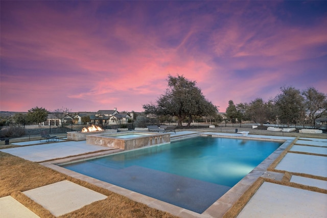 pool at dusk with an in ground hot tub, a patio, and an outdoor fire pit