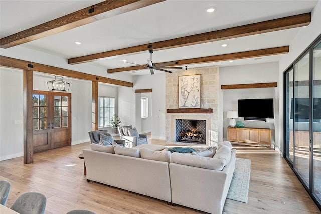 living room with ceiling fan, light hardwood / wood-style flooring, a fireplace, and french doors