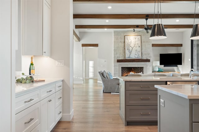 kitchen featuring pendant lighting, a fireplace, white cabinetry, gray cabinetry, and beam ceiling