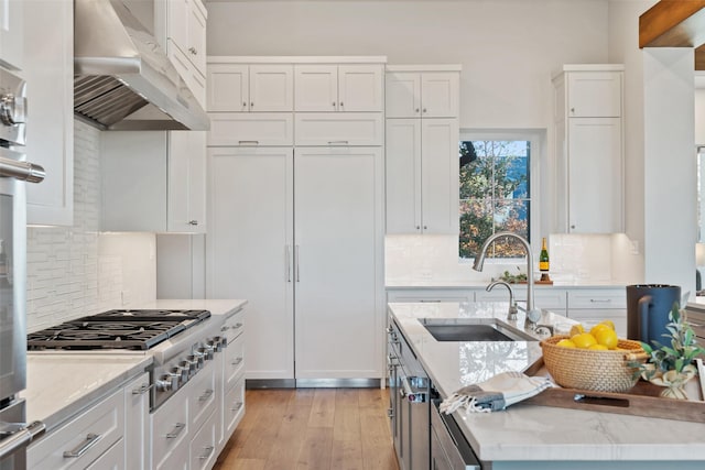 kitchen with stainless steel gas stovetop, white cabinetry, light stone countertops, and sink