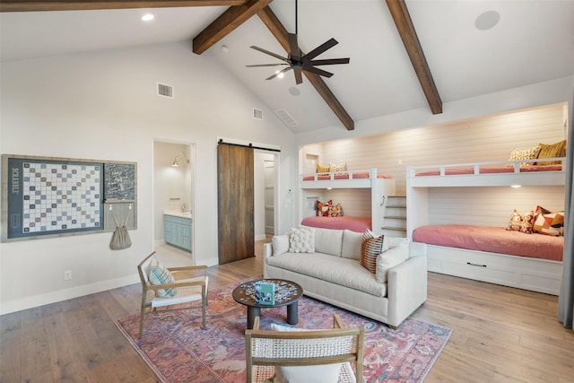 bedroom featuring ceiling fan, high vaulted ceiling, ensuite bathroom, wood-type flooring, and a barn door