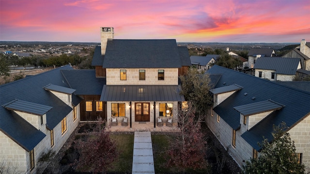 back house at dusk featuring a porch