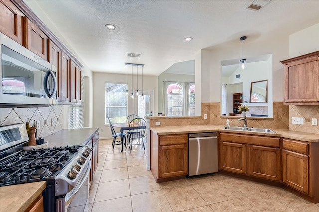 kitchen with sink, decorative light fixtures, plenty of natural light, and stainless steel appliances