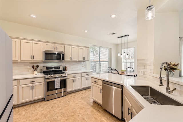 kitchen featuring sink, tasteful backsplash, appliances with stainless steel finishes, pendant lighting, and cream cabinets