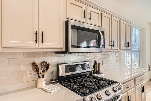 kitchen with tasteful backsplash, cream cabinetry, and appliances with stainless steel finishes