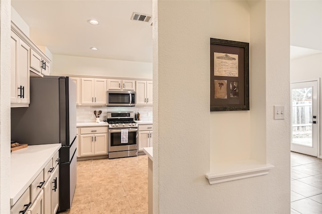 kitchen with stainless steel appliances, light tile patterned flooring, and backsplash