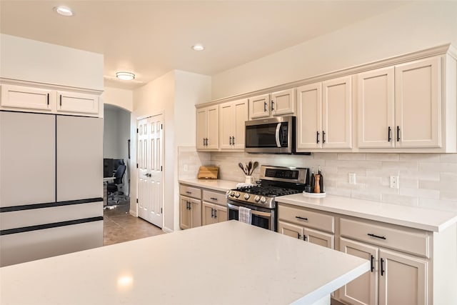 kitchen featuring stainless steel appliances, cream cabinets, and decorative backsplash