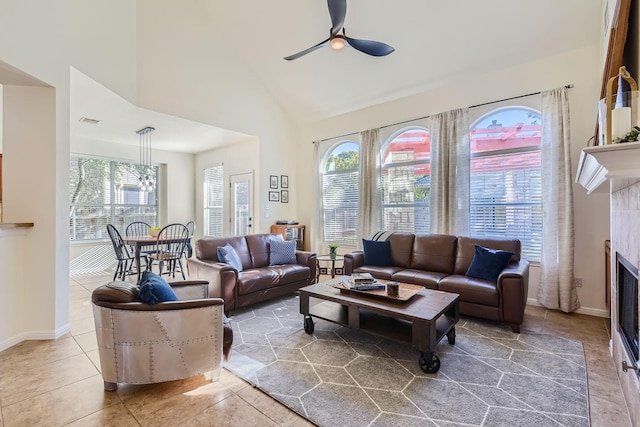 living room with a tiled fireplace, high vaulted ceiling, tile patterned floors, and ceiling fan