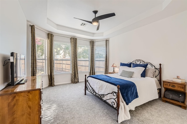 bedroom featuring a tray ceiling, light colored carpet, and ceiling fan