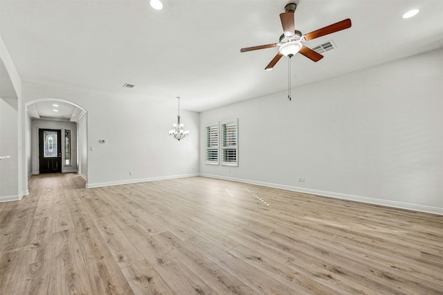 unfurnished living room with ceiling fan with notable chandelier and light hardwood / wood-style floors