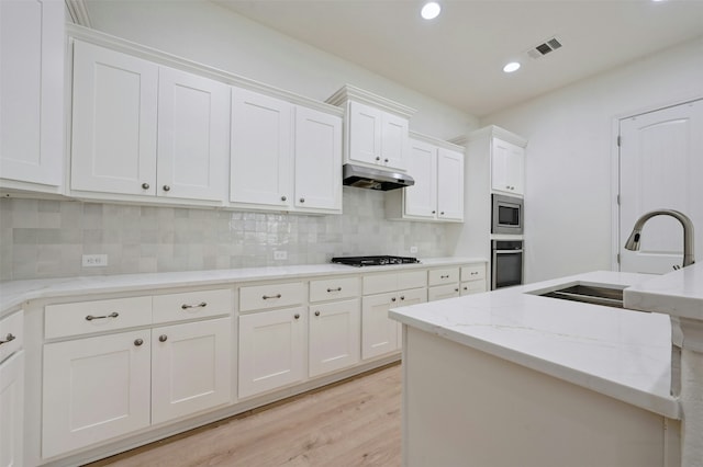 kitchen with light stone countertops, white cabinetry, appliances with stainless steel finishes, and sink