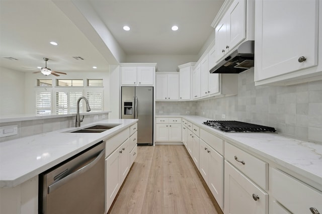 kitchen with sink, light stone counters, appliances with stainless steel finishes, light hardwood / wood-style floors, and white cabinets