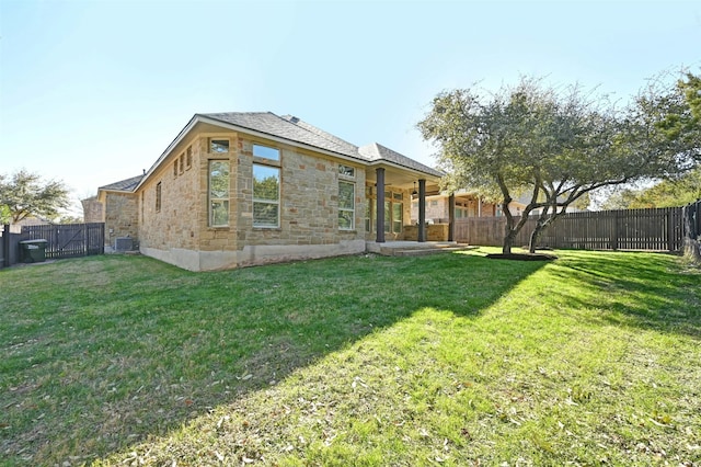 rear view of house featuring a yard and central air condition unit