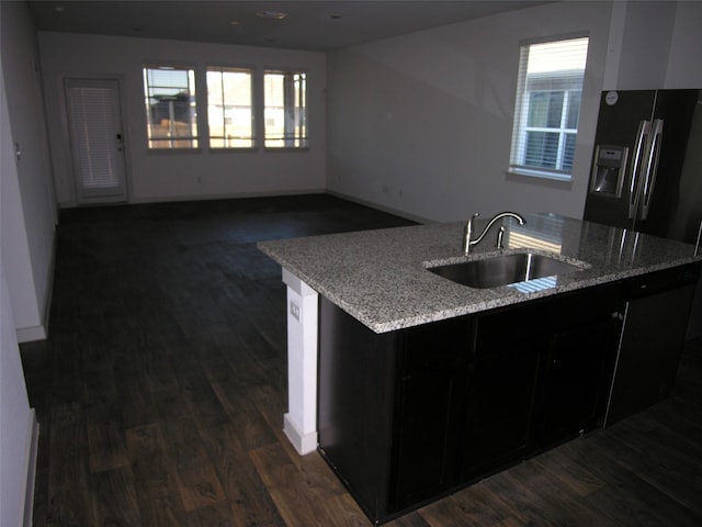 kitchen featuring light stone counters, sink, dark wood-type flooring, and black fridge