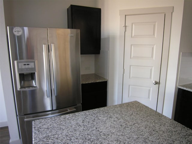 kitchen with light stone countertops, stainless steel fridge with ice dispenser, and decorative backsplash