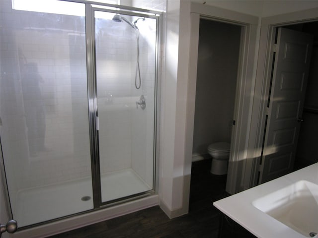 bathroom with hardwood / wood-style flooring, vanity, an enclosed shower, and toilet