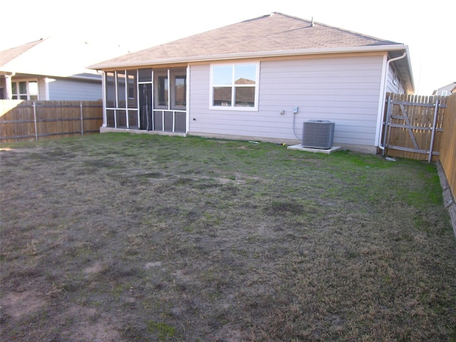 rear view of house featuring cooling unit, a lawn, and a sunroom